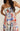 Woman wearing a colorful floral dress with a neutral background
