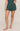 Person wearing green shorts on a beige background