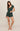 Woman wearing a green romper against a beige background
