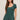 Woman wearing a green romper against a beige background