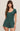 Woman wearing a green romper against a beige background
