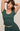 Woman wearing a green top and skirt with a neutral background