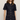 A woman modeling a dark indigo denim mini shirt dress with short sleeves, gold-tone buttons, and front patch pockets with decorative gold hardware, set against a plain light beige studio background.