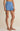 Person wearing blue shorts on a beige background