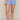 A model wearing light blue textured knit shorts with a scalloped hem, shown from the waist down against a neutral beige studio background.