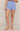 A model wearing light blue textured knit shorts with a scalloped hem, shown from the waist down against a neutral beige studio background.