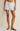 Person wearing light blue and white striped shorts on a beige background