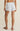 Person wearing light blue and white striped shorts on a beige background