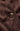 Close-up of a dark brown suede or velvety fabric with a visible button and stitched edge.