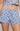 A close-up of a person wearing light blue waffle-knit shorts with a small dark floral print and a matching drawstring waist, paired with a matching cropped top.