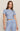 A woman modeling a light blue short-sleeve crop top and matching drawstring pants set with a small dark floral print, against a plain beige studio background.