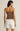Woman wearing a strapless brown top and white shorts on a beige background