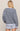 Person wearing a striped sweater and light blue shorts on a beige background