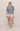 Woman wearing a striped sweater and light blue shorts on a beige background