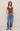 Woman wearing a brown tank top and blue jeans against a beige background