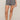 A model wearing a pair of high-waisted shorts with a black and white geometric pattern, shown from the waist down against a solid beige studio background.