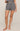 A model wearing a pair of high-waisted shorts with a black and white geometric pattern, shown from the waist down against a solid beige studio background.