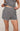 A close-up of a model wearing patterned shorts and a matching top, showing the fabric print and waist details against a plain beige background.
