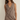 Woman wearing a brown sleeveless dress against a plain background