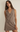 Woman wearing a brown sleeveless dress against a plain background