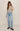 Woman wearing a striped shirt and blue jeans on a plain background