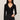Woman wearing a black long-sleeve top and dark jeans against a plain background