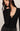 Woman wearing a black long-sleeve top with a deep neckline against a neutral background