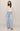 A woman modeling a cream long-sleeve V-neck top and light-wash wide-leg blue jeans against a plain beige studio background.