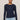 A woman modeling a navy blue long-sleeve knit top with a boat neckline, paired with light blue jeans, against a solid light gray background.