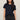 Woman wearing a black t-shirt and dark jeans against a plain background