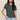 Woman wearing a green t-shirt and blue jeans against a plain background
