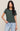 Woman wearing a green t-shirt and blue jeans against a plain background
