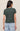 Person wearing a green t-shirt and light blue jeans on a beige background