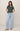 Woman wearing a green t-shirt and light blue jeans on a beige background