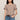 Woman wearing a brown t-shirt and blue jeans against a beige background