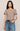 Woman wearing a brown t-shirt and blue jeans against a beige background