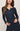 A woman wearing a dark navy ribbed long-sleeve henley top with a buttoned split neckline, shown against a plain light beige studio background.