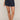Person wearing navy blue shorts on a beige background
