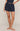 Person wearing navy blue shorts on a beige background