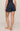 Person wearing navy blue shorts on a beige background