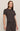 Woman wearing a dark brown t-shirt and pants on a beige background