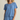 Woman wearing a blue textured top and shorts set on a beige background