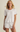 Woman wearing a white ribbed t-shirt and shorts set on a beige background