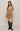 Woman wearing a brown dress with short sleeves and black boots on a beige background