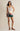 Woman wearing a white tank top and floral skirt on a beige background