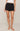 Person wearing black shorts with white polka dots on a beige background