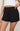 Black polka dot shorts worn by a person on a plain background