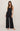 Woman wearing a black polka dot jumpsuit on a plain background