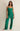 Woman wearing a green jumpsuit against a plain background