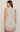 A woman shown from the back wearing a sleeveless light taupe-gray mini dress with a lace hem, photographed against a plain light beige studio background.